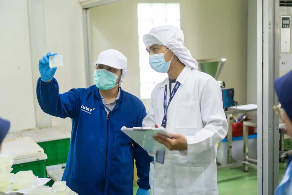 Staff Quality Control (QC) sedang memeriksa kejernihan dan fisik produk sabun batang transparan di lini produksi pabrik maklon PT Adev.