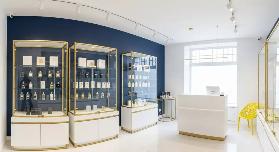 Desain interior toko parfum mewah dengan nuansa warna biru navy dan putih, lengkap dengan etalase kaca dan pencahayaan LED.