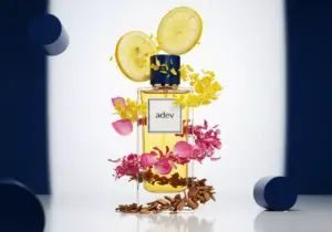 Botol parfum Adev dikelilingi bahan alami lemon, mawar, dan cendana, mengilustrasikan komposisi notes parfum