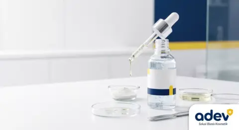 Foto close-up botol serum skincare transparan dengan pipet di meja produksi laboratorium maklon bersih, tekstur serum bening dengan bahan aktif, palet navy kuning putih